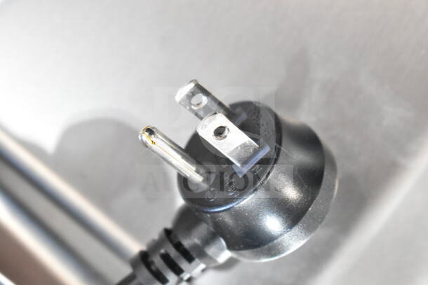 Close-up of 115-volt plug for Elkay ENKLZS8WS_1A hands-free bottle filling station, showing prongs and markings.
