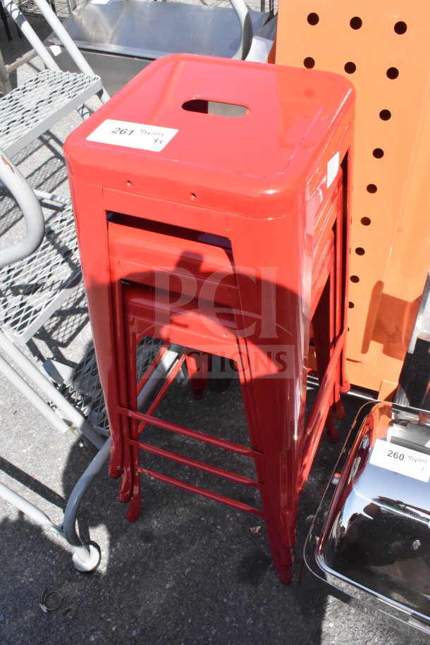 Three new scratch and dent red Tolix-style bar stools, stacked, with tags indicating lot number 261.