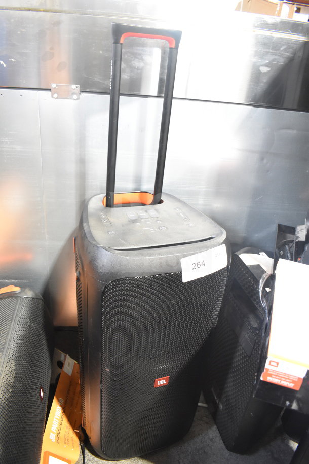 JBL Partybox 310 speaker with handle, black mesh front, and JBL logo. Condition appears used with visible wear. Tag labeled "264."