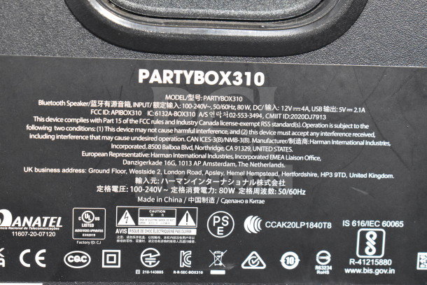 Label image of the JBL Partybox 310 speaker showing model details, inputs, manufacturing info, compliance logos, and voltage specifications.