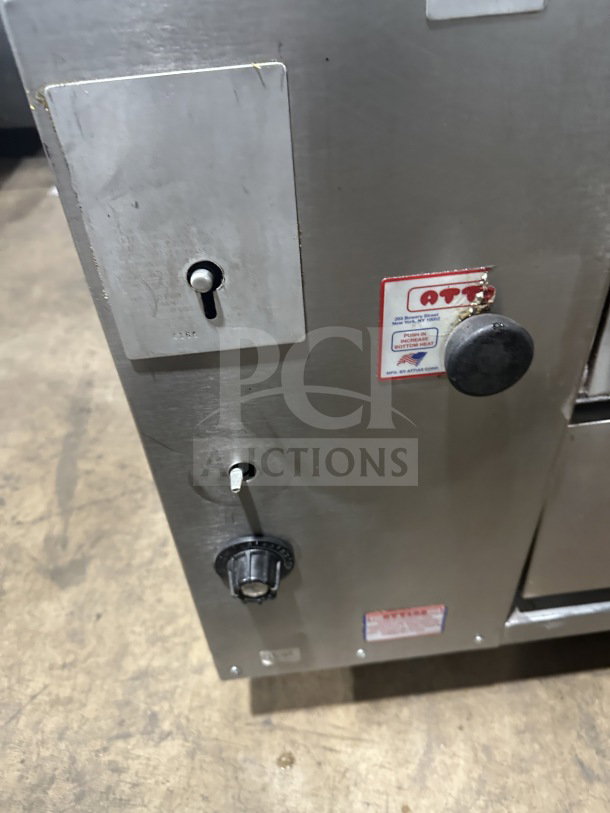 Attias stainless steel gas-powered double deck pizza oven, commercial countertop model, with control knobs and labeled panel.