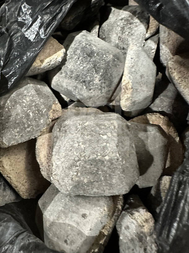 Bag of gray porous lava rocks typically used for grilling or decorative purposes.