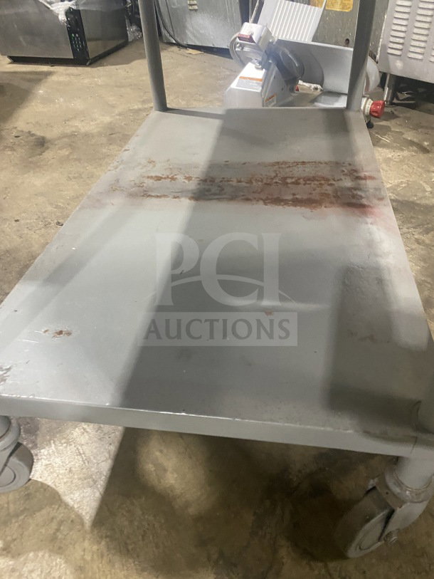 Commercial stainless steel two-compartment equipment stand on casters, visible wear, sturdy design, mobile functionality.