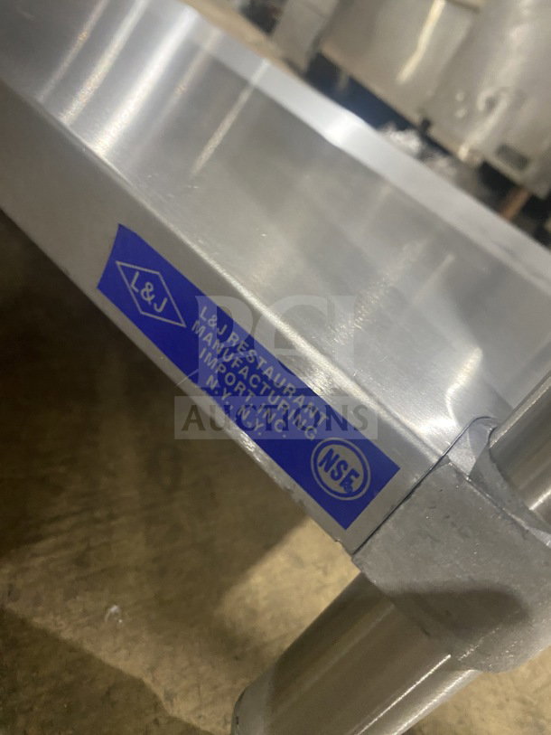 L&J stainless steel two-compartment equipment stand on legs, featuring NSF certification label. Ideal for commercial use.
