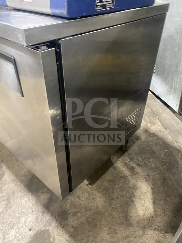 Commercial two-door stainless steel undercounter refrigerator or freezer, well-maintained, sturdy handle, minor surface wear.