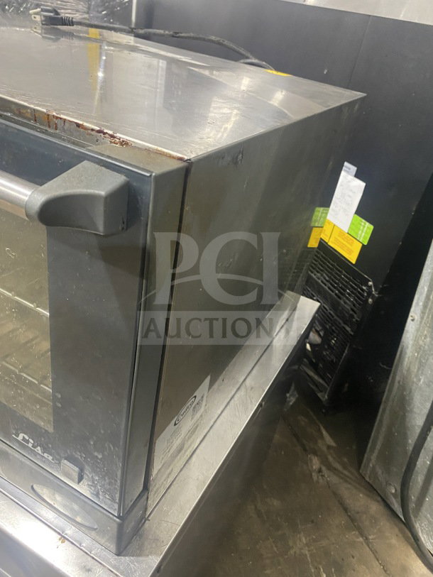 Unox Cadco Lisa Series XAF013 convection oven, half-sized, with metal racks, 120V. Used condition, visible side wear. Model and serial labels shown.