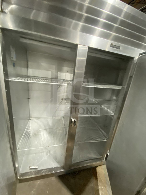 Traulsen stainless steel triple door reach-in freezer, model G31010, with poly coated wired racks on casters, electric power.