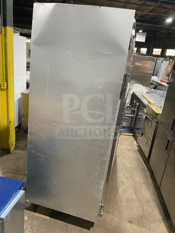 Traulsen stainless steel triple door reach-in freezer, Model G31010, with poly-coated rack, on casters, shown in warehouse.
