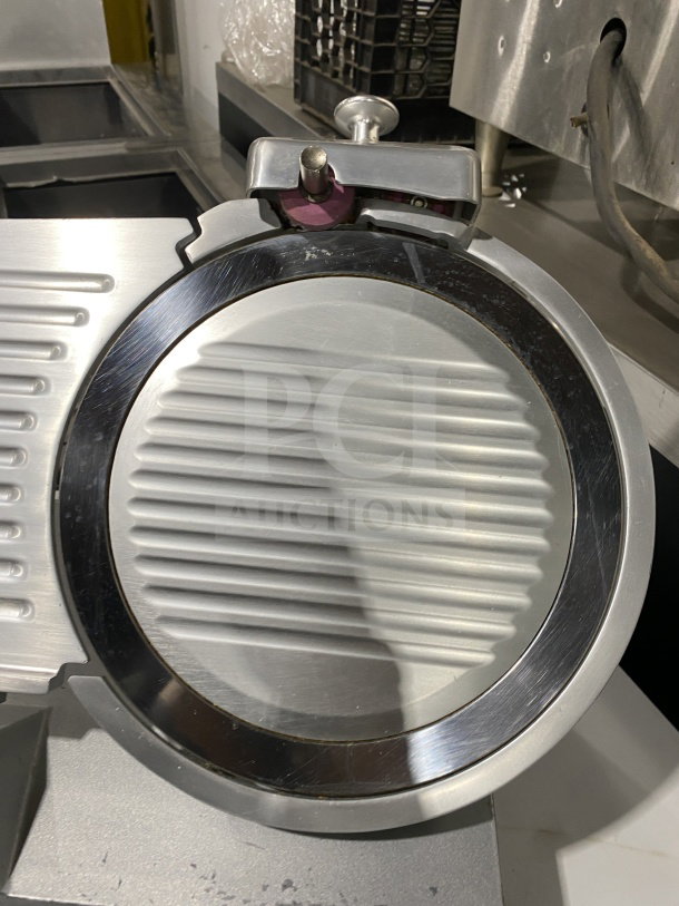 Commercial stainless-steel electric countertop meat slicer, mounted on legs. Features sharp circular blade, excellent condition.
