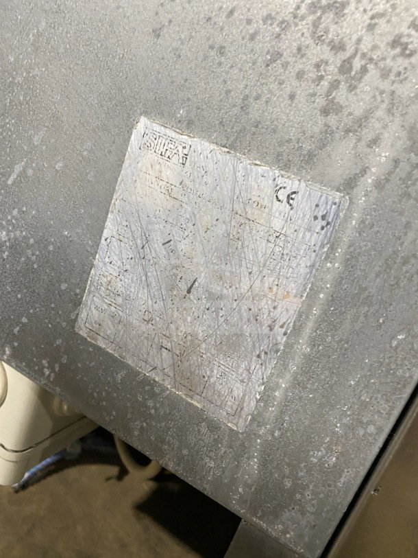 Commercial stainless-steel open-air merchandiser, electric powered, visible wear, manufacturer's plate with markings.