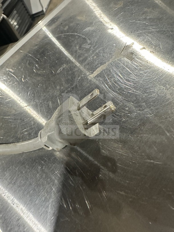 Power plug of Solwave Commercial Microwave Model 180MW1000SS, showing a 120V connector on a scratched stainless surface.