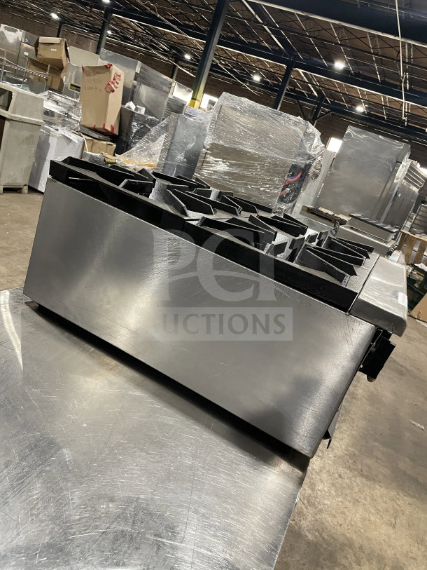 L&J Brands stainless steel gas-powered 4-burner countertop hot plate in a warehouse setting. Appears in good condition.