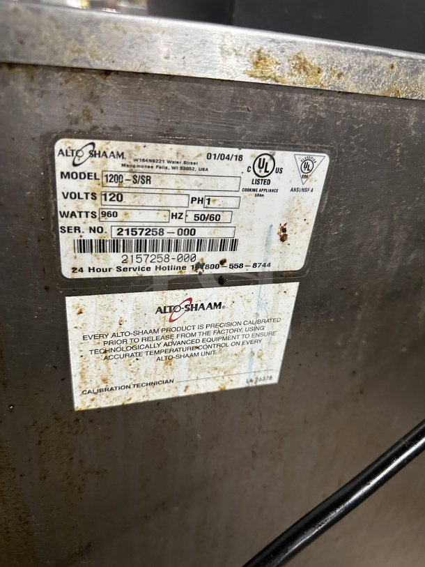Alto Shaam stainless steel electric holding cabinet, Model 1200S, SN M10673352021, 120V, on casters, with calibration labels.