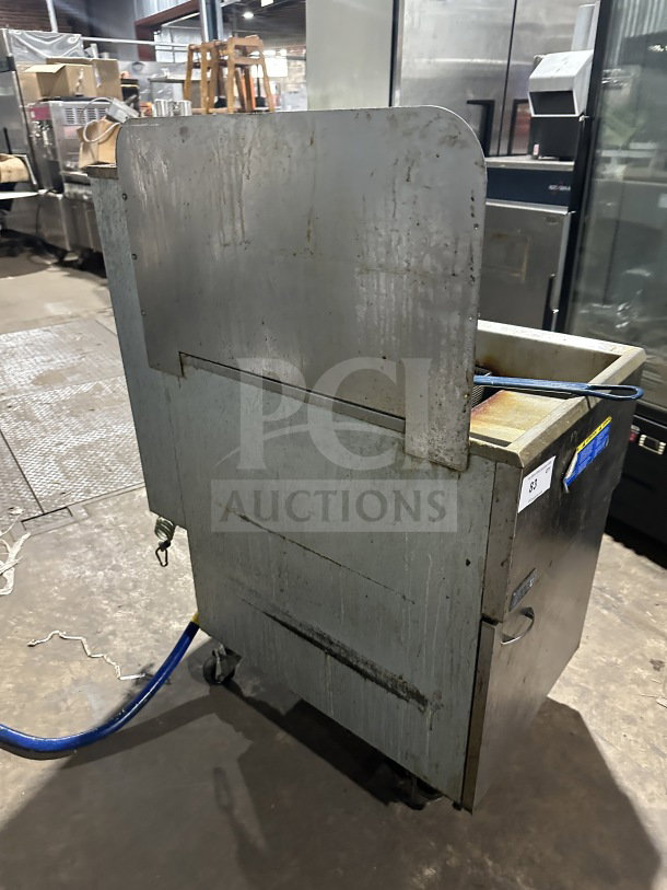 Pitco 65C+ commercial stainless steel natural gas fryer with back splash and basket. On casters. Visible wear. SN: G17HC052060.