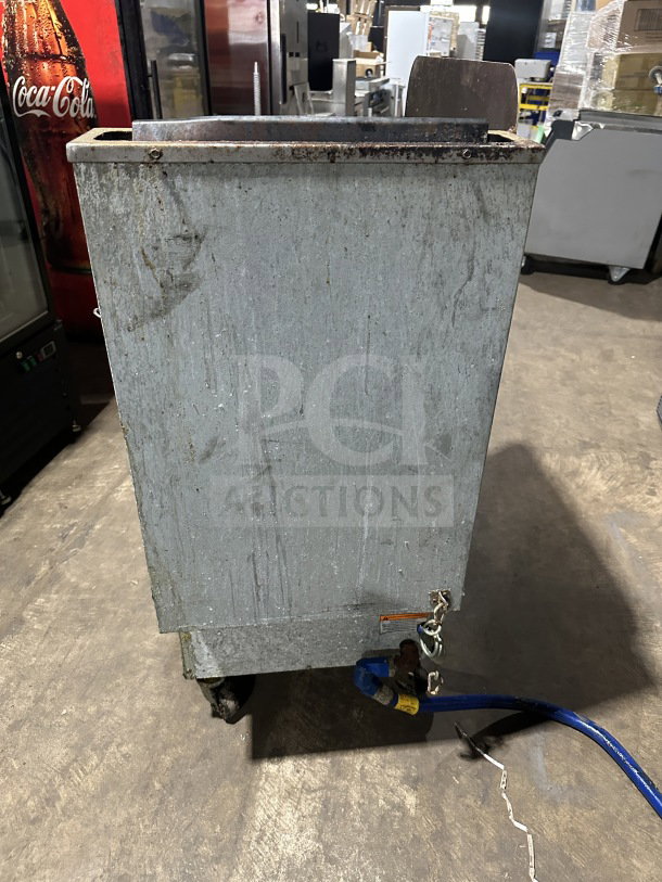 Pitco 65C+ commercial stainless steel gas fryer with back splash, frying basket, and casters. Signs of wear visible.
