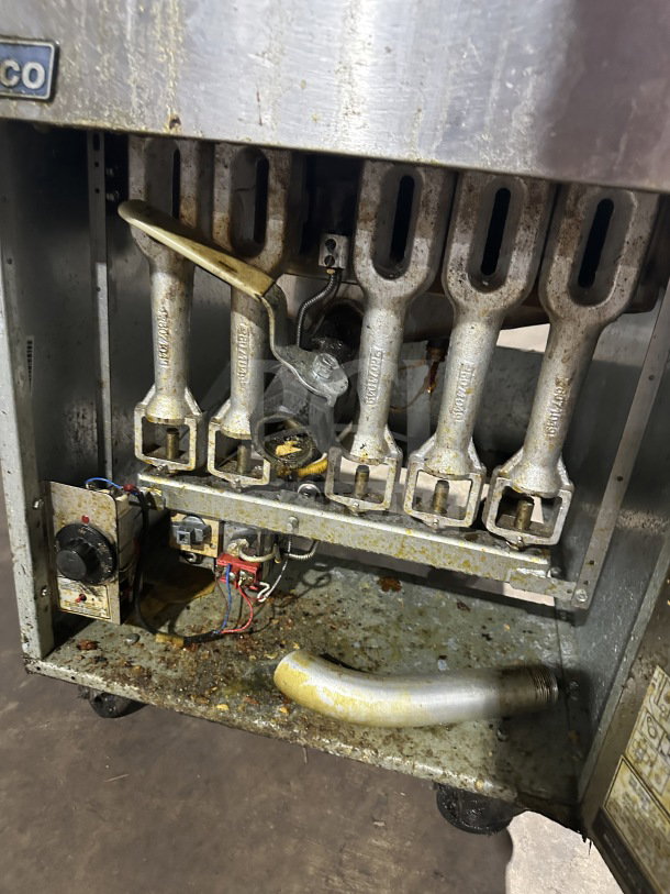 Pitco 65C+ commercial stainless steel natural gas fryer, visible burners, worn condition, on casters, includes frying basket.