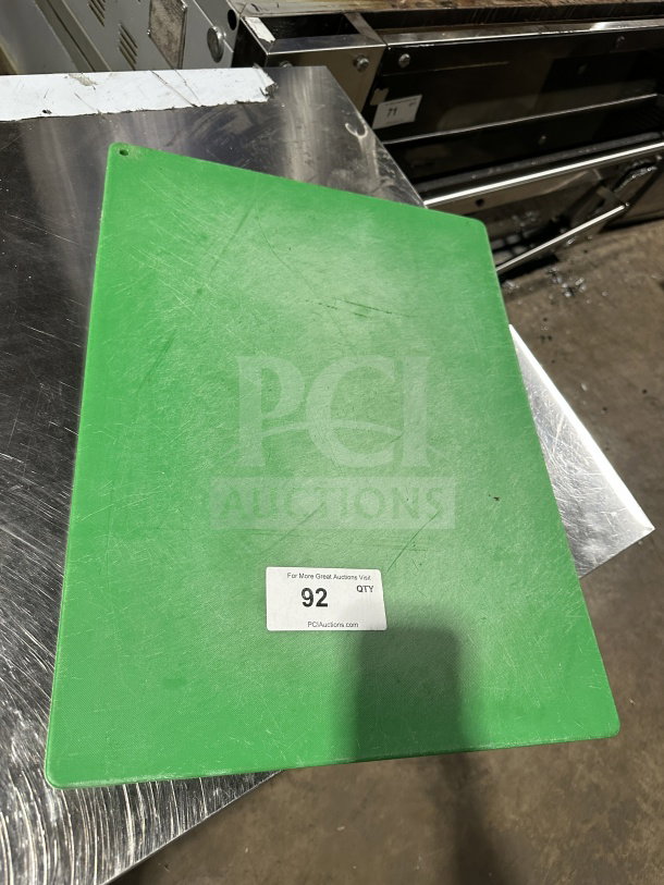 Used green commercial plastic cutting board with visible scratches. Item label indicates auction lot 92.