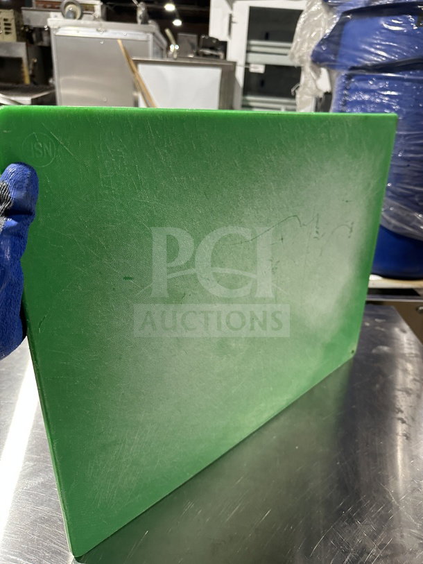 Green commercial plastic cutting board, used condition with visible knife marks, approximate size 24x18 inches.