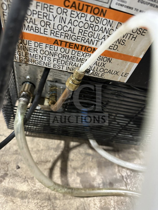 Manitowoc stainless steel undercounter ice machine, model UNP0200A-161. Visible caution label, rear cooling components.