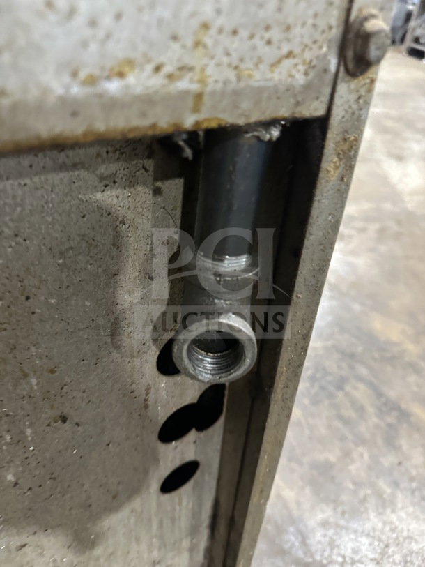 Commercial stainless steel gas range detail showing a pipe connector and rust. Auctioned for its sturdy build and utility.