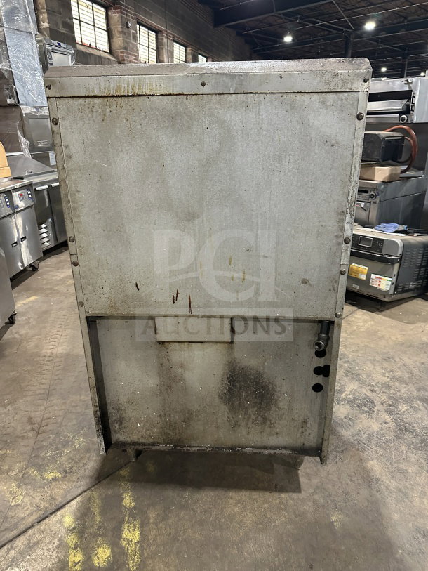 Commercial stainless steel gas range with 4 open burners, 12" charbroiler, standard oven base, wired rack, on legs. Used condition.