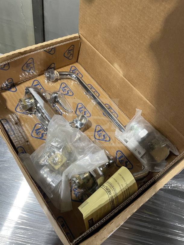 T&S B-1128 commercial wall-mounted workboard faucet in original packaging, with chrome finish, includes installation parts.