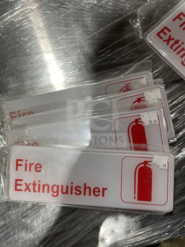 Brand new Thunder Group commercial fire extinguisher signs, red text and icon on white plastic, packaged individually.