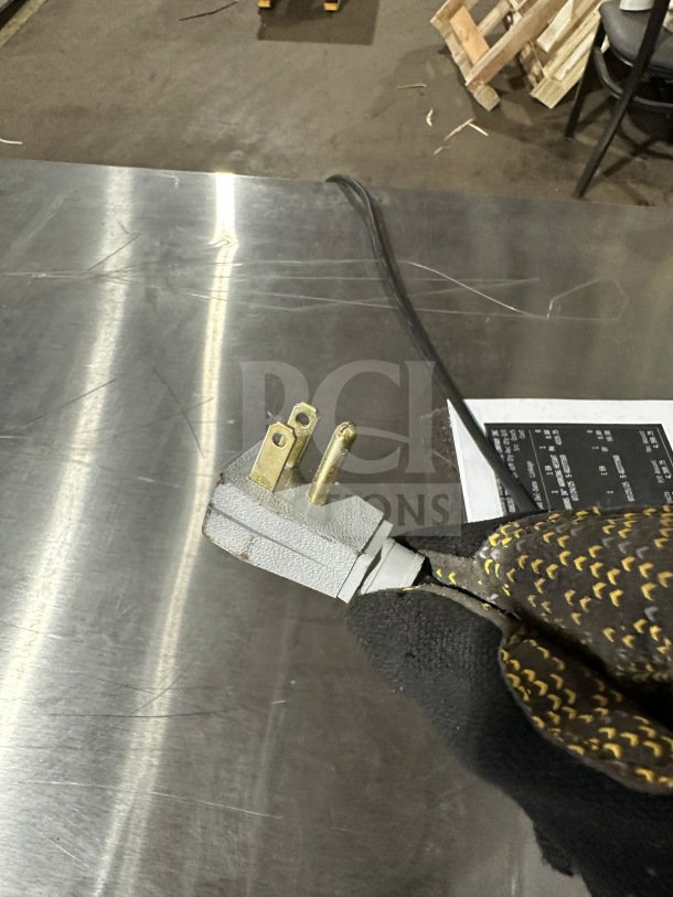 Close-up of a power plug connected to a stainless steel surface, likely part of the True TUC-72-HC refrigerator.
