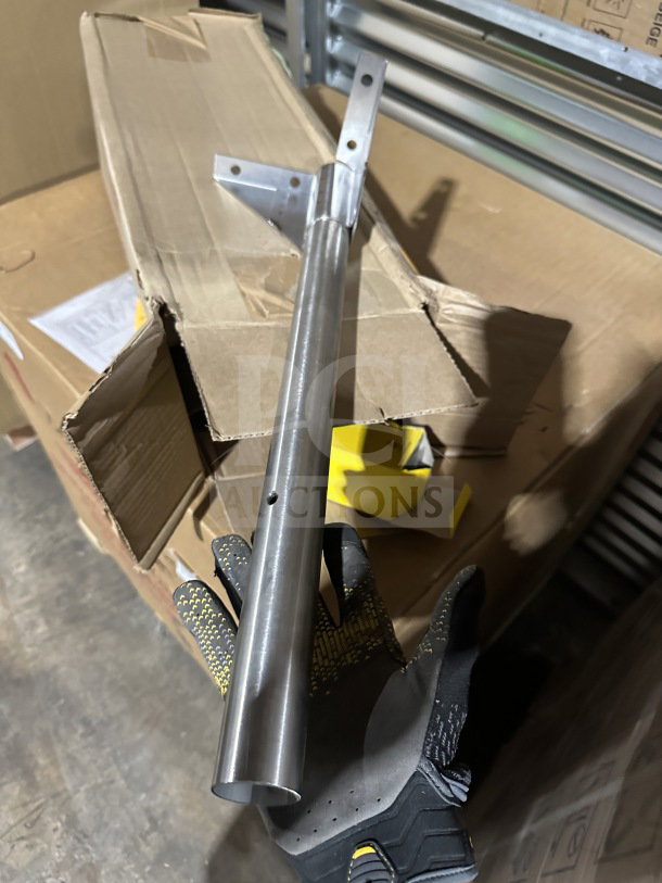 Alt text: Metallic component held above a partially open cardboard box on a warehouse floor.
