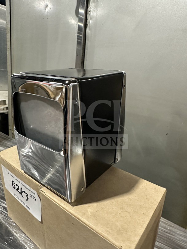 Brand new commercial chrome tallfold napkin dispenser on cardboard box. Sleek design, reflective finish, excellent condition.