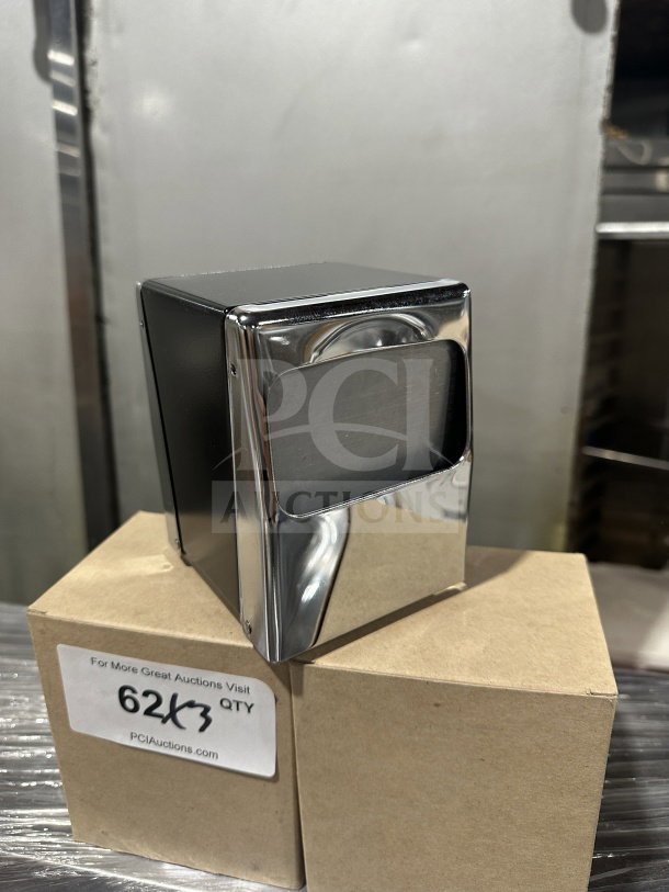 Brand new commercial chrome tabletop tallfold napkin dispenser, sleek design, perfect condition, placed atop a labeled box.