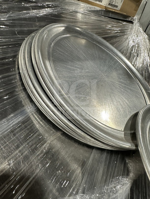 New commercial aluminum wide-rim pizza pans, stacked, wrapped in plastic. Excellent condition. 7 pans per bid.