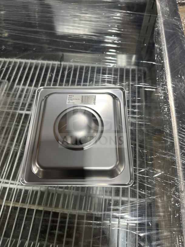Brand new Winco 1/6 size solid stainless steel steam table pan cover, model SPSCS, on display.
