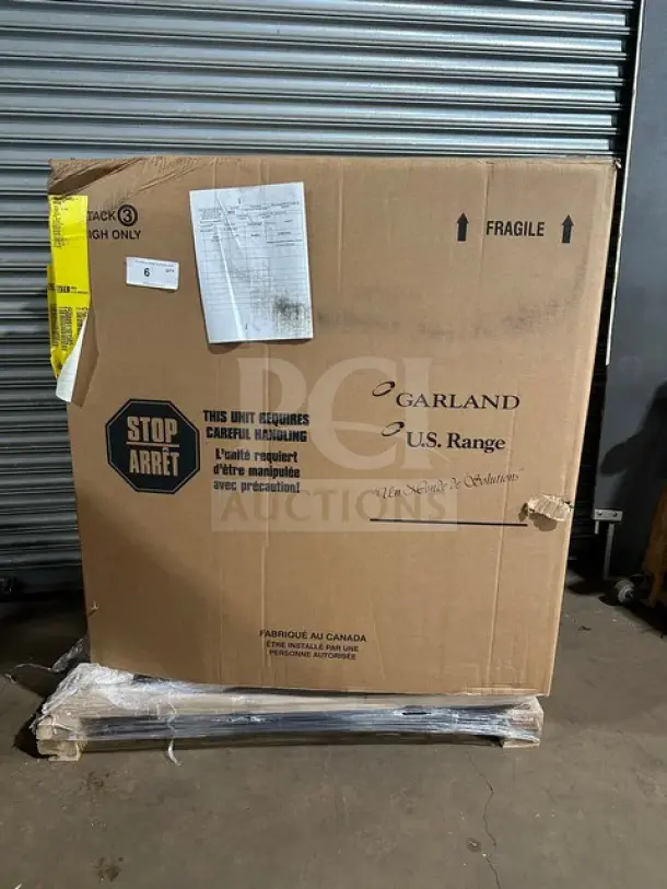New Garland C18-1M-5001 gas range griddle, 18-inch, 30000 BTU, modular, on legs. Box shows handling labels and damage.