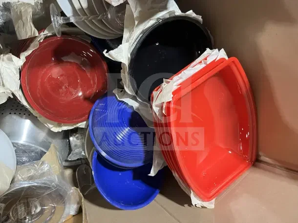 Large box filled with new colorful dishware, cups, and poly bowls. Includes red, blue, black items wrapped in paper.
