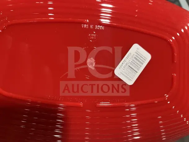 Large red dish with barcode sticker. Part of a box filled with new dishware and cups.