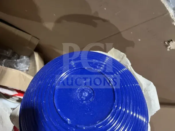 Large box filled with new dishware, cups, and poly bowls. Blue plate shown with embossed markings for identification.