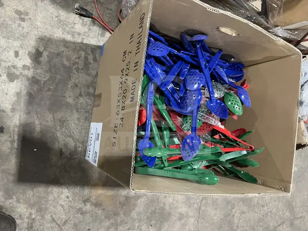 Assorted poly serving spoons and tongs in multi colors, blue, red, and green, in new condition in a large cardboard box.