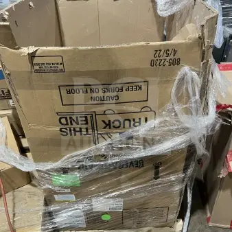 Large cardboard box filled with new dishware, cups, and poly bowls, wrapped in plastic. Box shows handling labels and warnings.