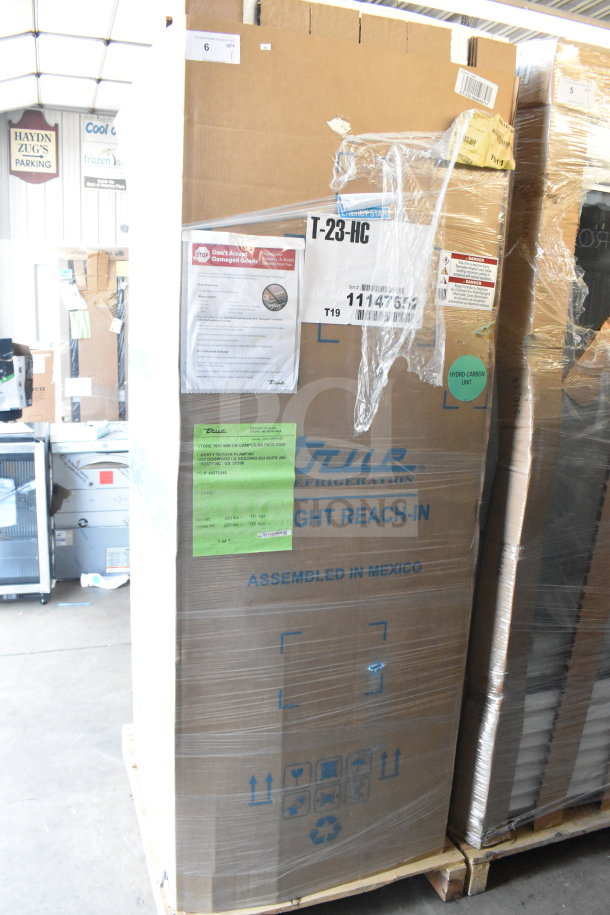 Brand new True T-23-HC commercial cooler in packaging, 115V, single door, scratch and dent condition, labels visible.