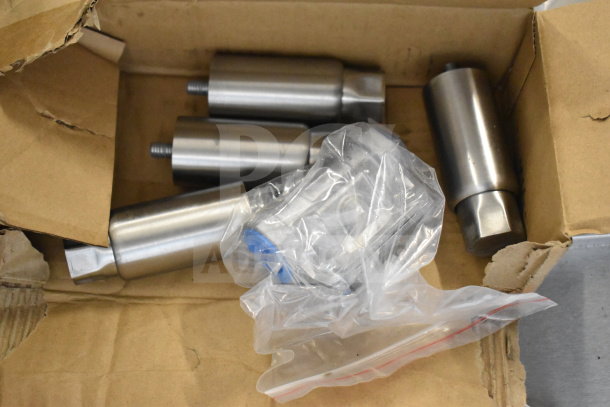 A box containing cylindrical metal parts in new condition, wrapped in plastic packaging.
