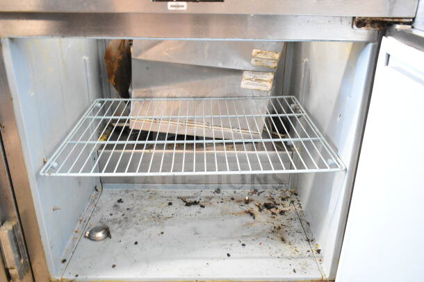 Delfield sandwich salad prep table interior with wire shelf. Missing bolts for Bain Marie lid. Marks and wear visible.