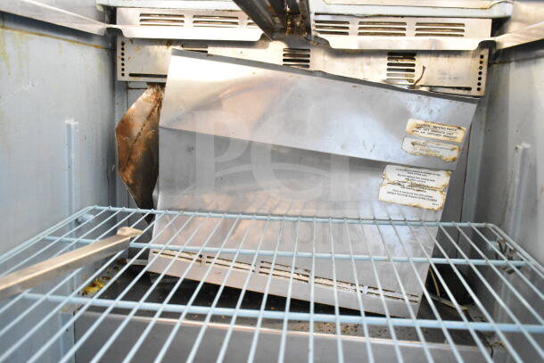 Delfield commercial sandwich salad prep table interior, missing bolts for Bain Marie lid setup, visible wear, labels present.