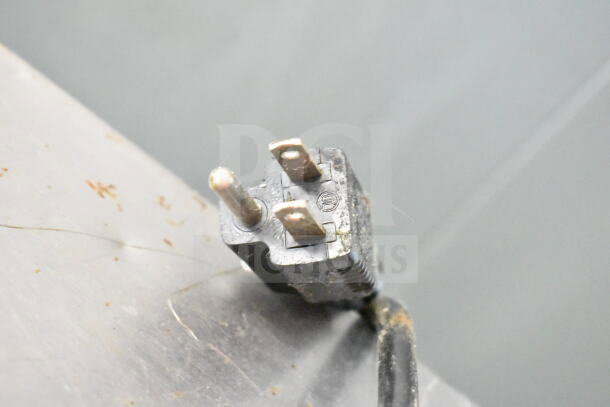 Plug of Frigoglass UR30-CC commercial mini cooler; standard 115V, 1 phase. Slight wear visible on plug surface.