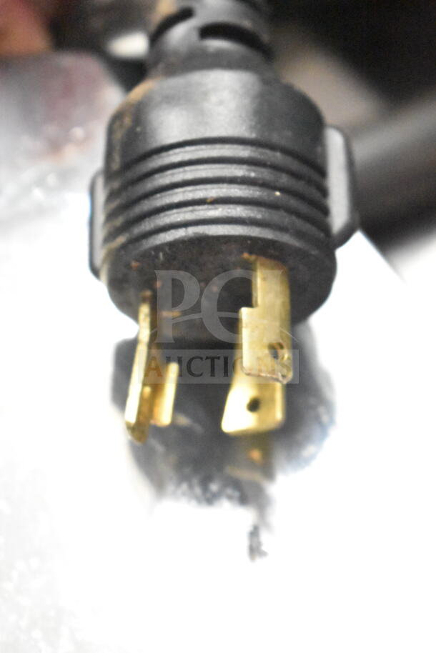 Close-up of a power plug for a Schaerer Barista Espresso Machine, displaying brass prongs in used condition.
