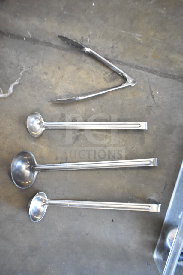 Set of stainless steel ladles and metal tongs on concrete surface, part of 57 item auction lot.