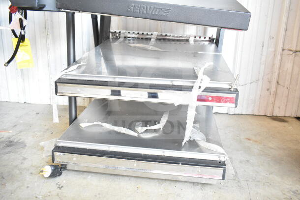 ServIt 423OAM65D 24" heated display merchandiser with slanted 2-shelf design. Features stainless shelves and visible power cord.