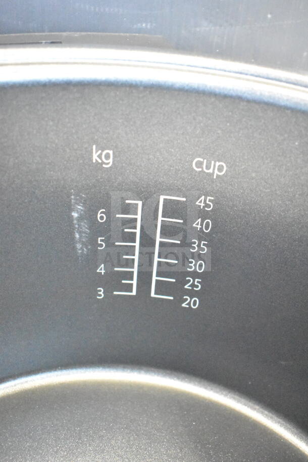 Brand new Avantco 177RCSB90 rice cooker interior, showing measurement markings in kg and cups, minor scratches visible.