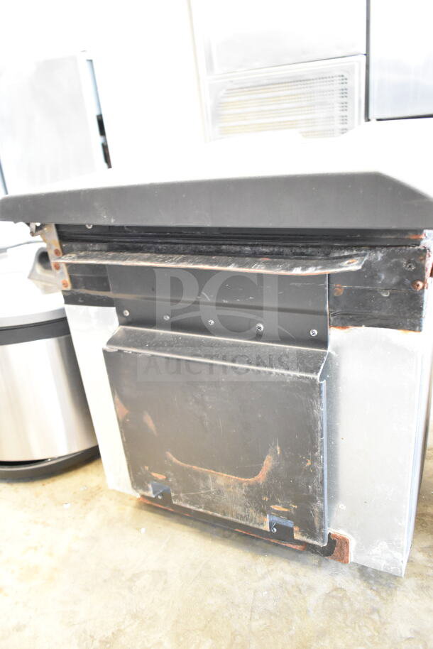 Mini cooler with a metal exterior and black top. Shows signs of wear and rust along edges, indicating moderate use.