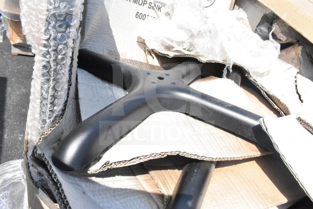 Black base of a brand new mop sink set, partially wrapped in bubble wrap inside a cardboard box, visible scratch and dent condition.